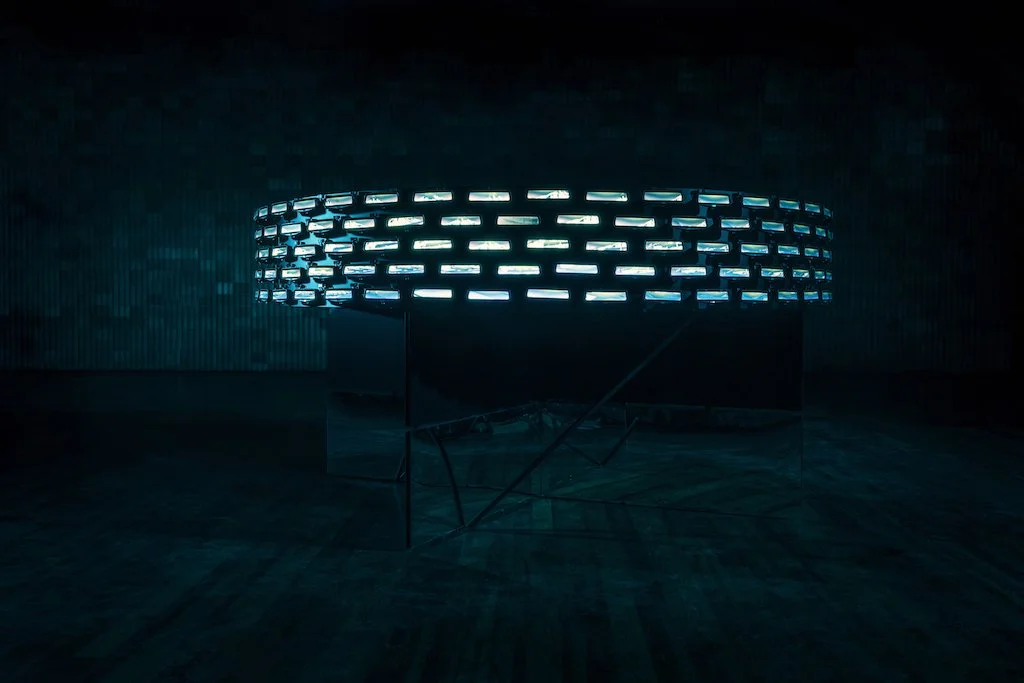 The full Horizon ring sculpture suspended and illuminated in a darkened gallery