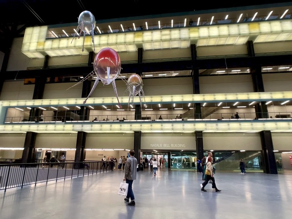 Three aerobes suspended near the Turbine Hall entrance, showing their translucent spherical bodies and trailing soft-robotic tentacles
